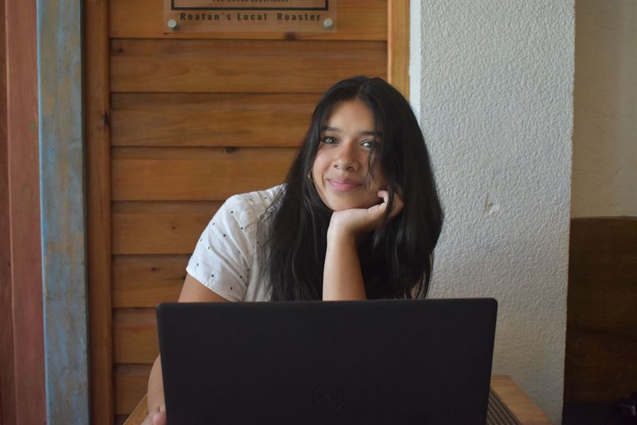 Sofia resting her chin on her hand and smiling over her open laptop