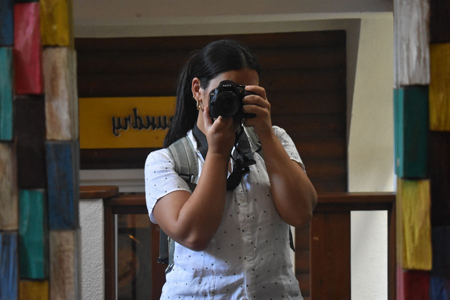 Sofia taking a photo with a camera in a colorful, creative space